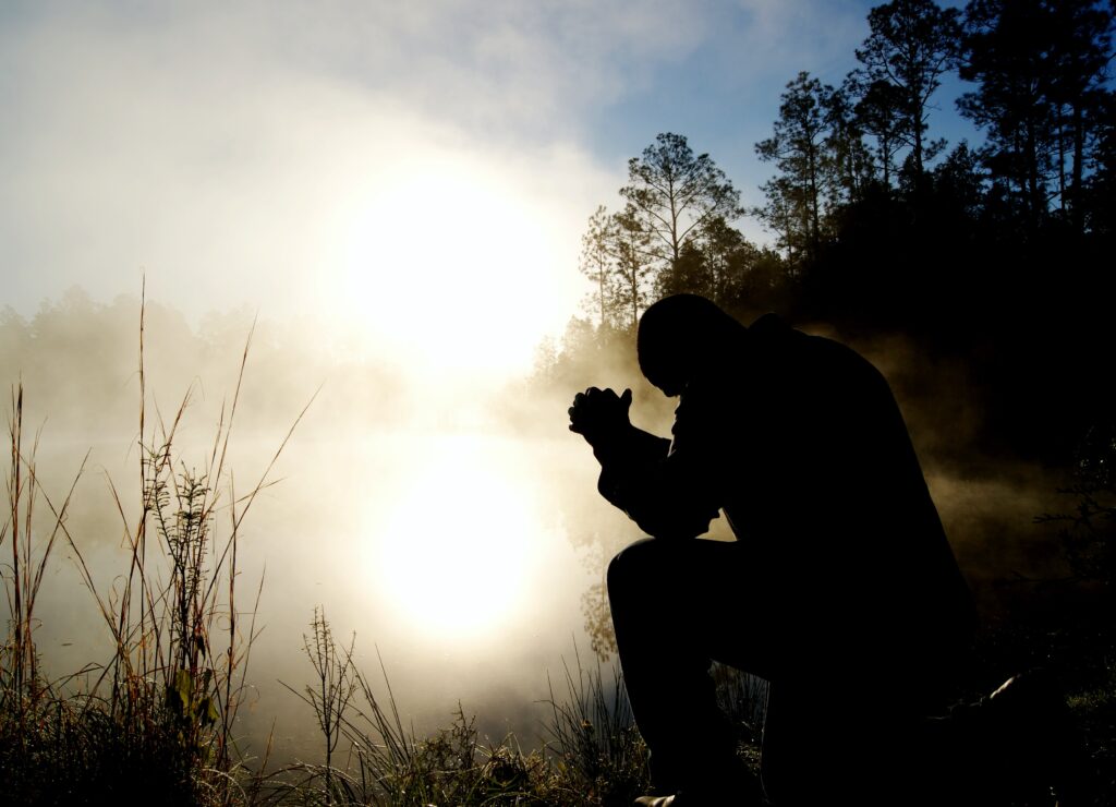 мужчина молится на природе 